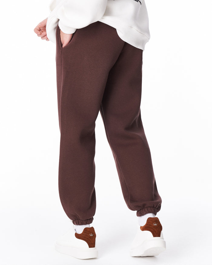 Martin Valen brown "Fell Better" joggers close-up at the waist, embroidered lettering shown as hand lifts sweatshirt